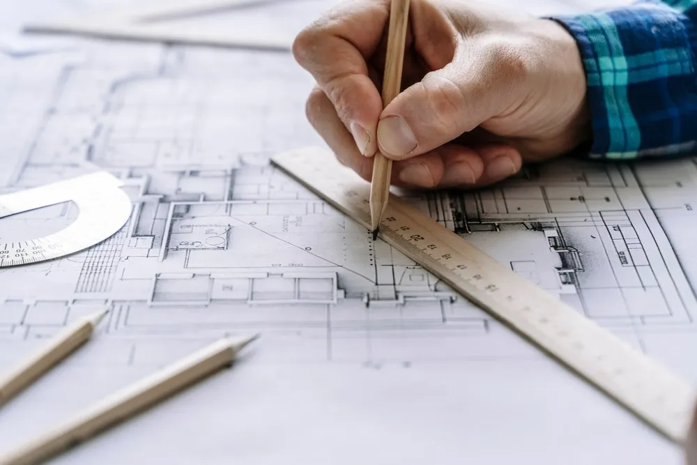 Architect reviewing residential building plans with a ruler during the design stage.